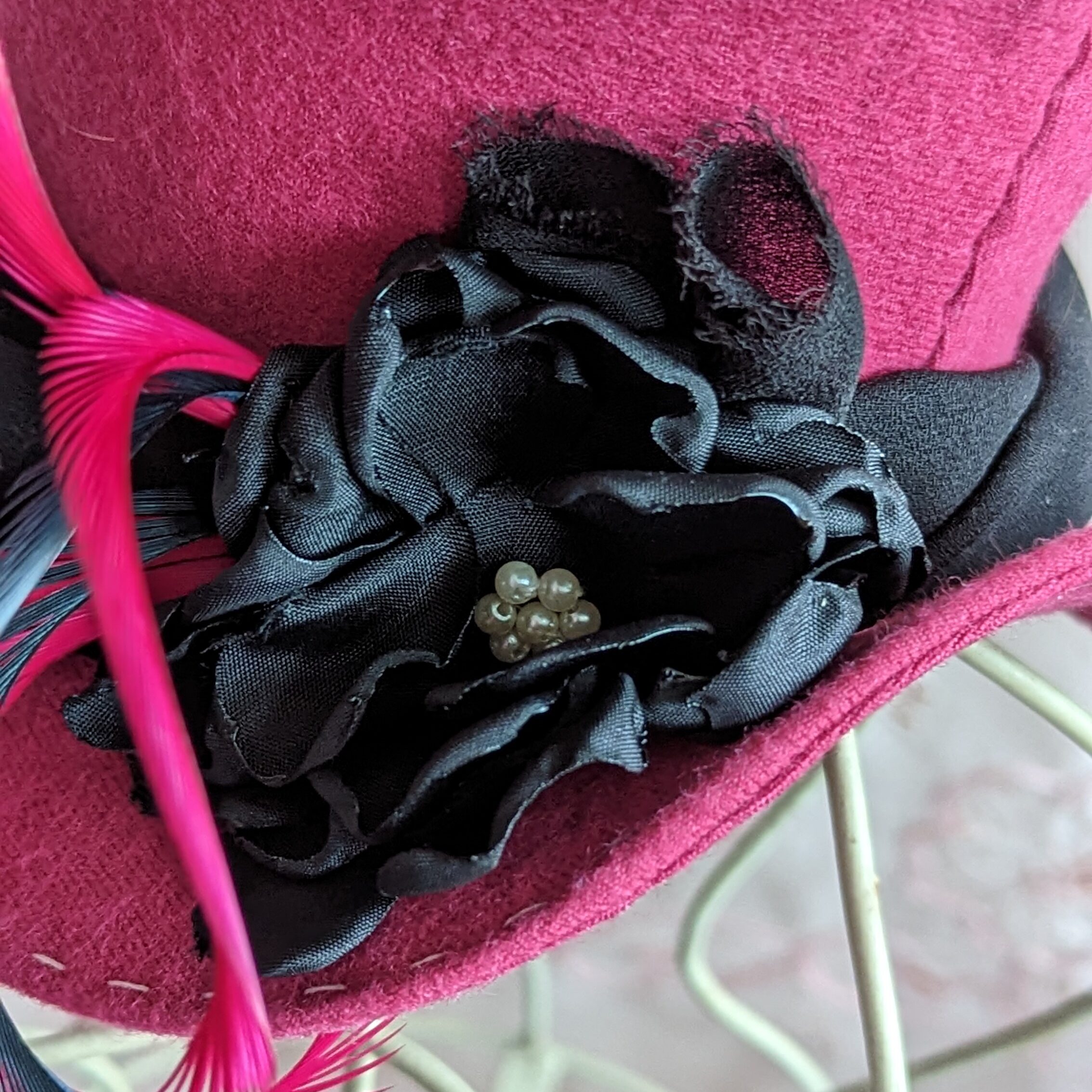 a fabric flower on a dolls top hat